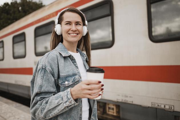 Woman listening to music next to train